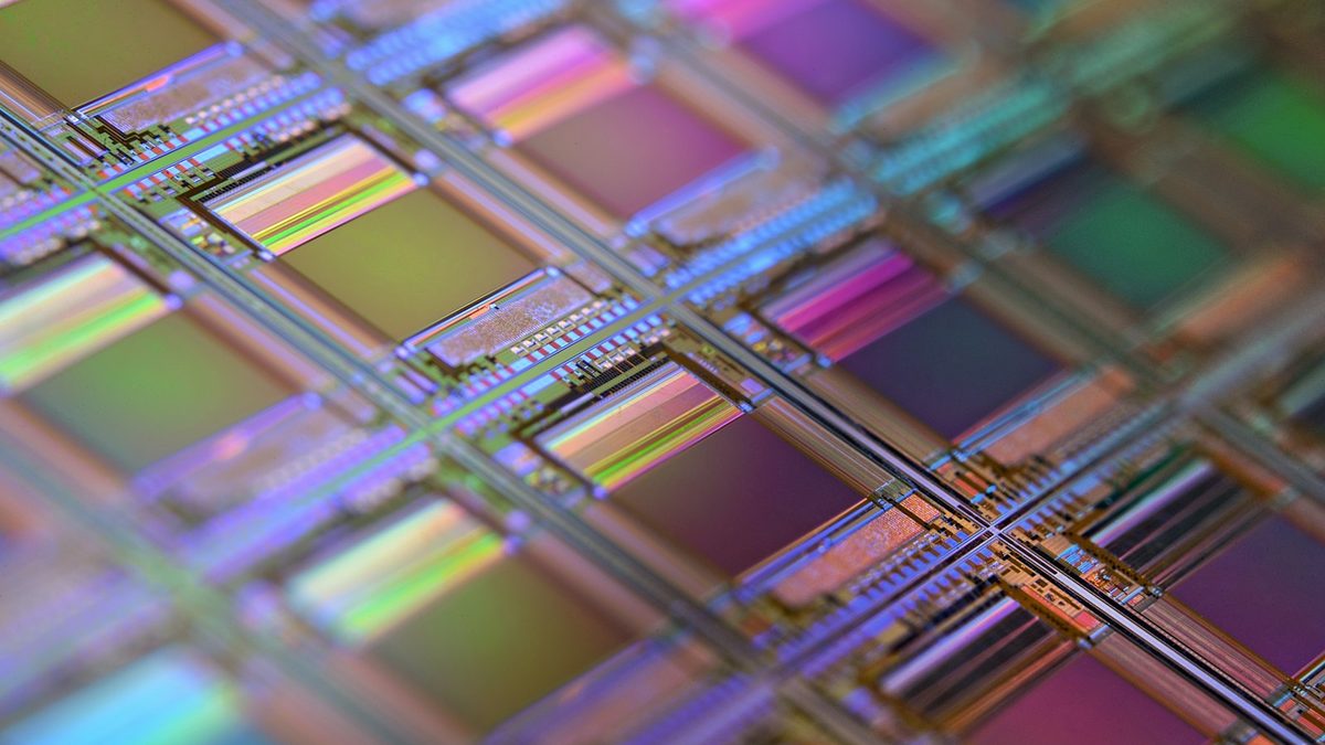 A close-up of a silicon wafer showing a grid of iridescent microchip dies
