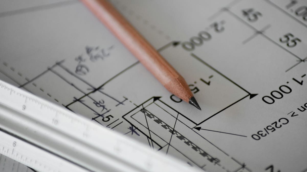 A pencil and scale rule resting on a printed technical construction drawing.