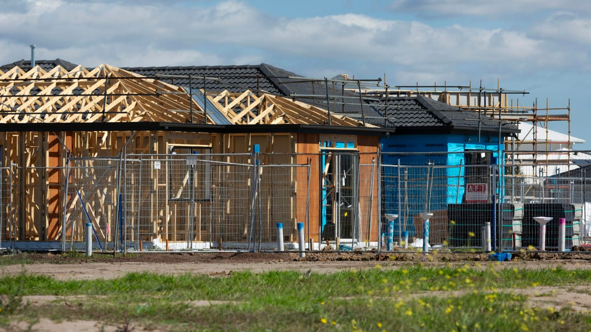 Single-storey houses under construction with exposed timber framing and roof trusses.