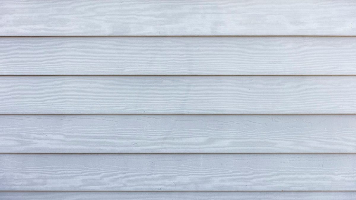Courses of pale grey horizontal lap siding with a moulded wood-grain texture, photographed straight on.