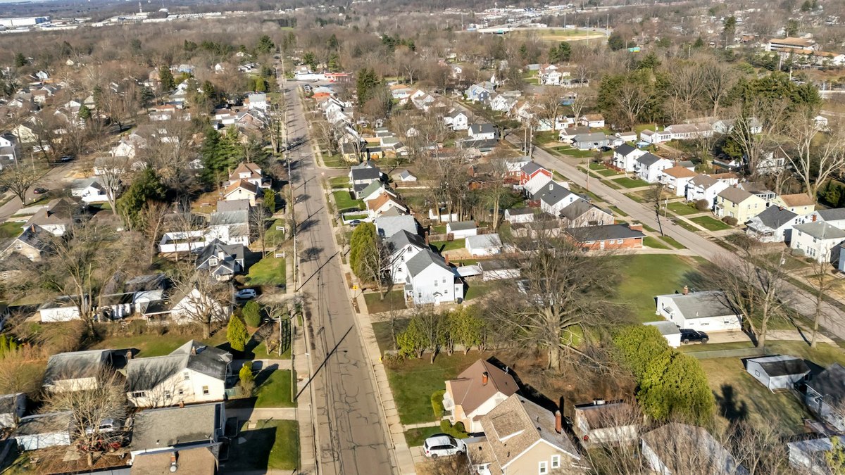 Aerial view of an American suburban neighbourhood of detached houses along a long residential street in winter.